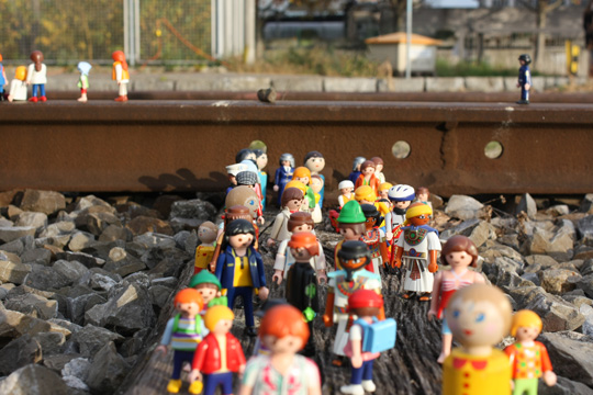 Eine Ansammlung von Playmobil-Figuren, platziert zwischen Bahnschienen auf der stillgelegten Bahntrasse des Hafenareals in Basel. Exemplifiziert den Aspekt Diversität in unserer Welt.